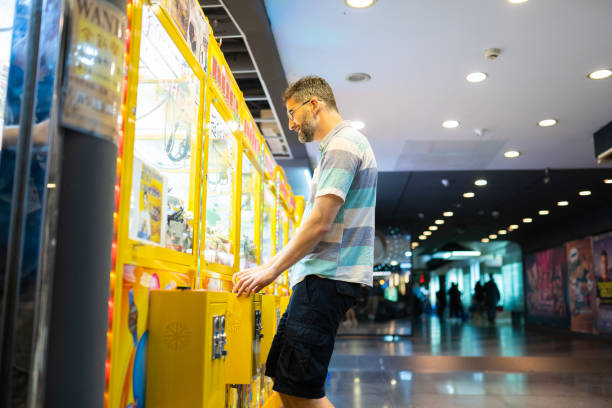 Side view of man  Playing the Claw Game in an Arcade, in a shopping mall in Taipei