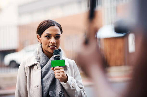 She's got an update on the story Shot of an attractive young news reporter covering a story outdoors in the city newsreader stock pictures, royalty-free photos & images