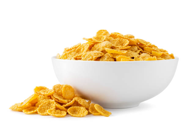 istock Cornflakes in a plate and scattered on a white. Isolated 1187168253