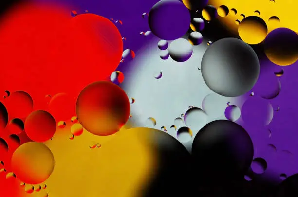 Colorful abstract background. Red purple yellow white black circles and oil bubbles in the water. Close up. Macro abstraction. Rainbow oil pattern and texture.
