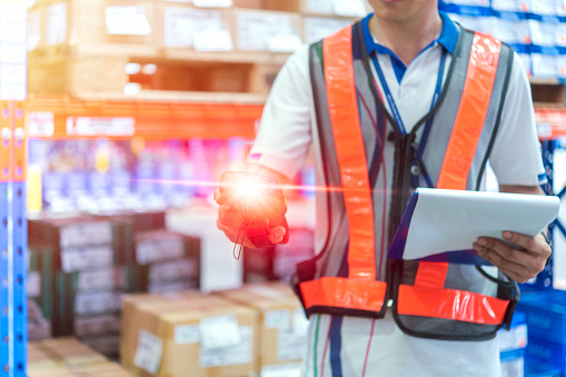 Closeup of unrecognizable warehouse worker doing stock inventory check by using handheld bar code scanner.