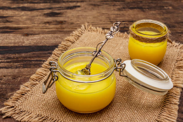 pure or desi ghee (ghi), clarified melted butter. healthy fats bulletproof diet concept or paleo style plan. glass jars, silver spoon on vintage sackcloth. wooden boards background - kitchen utensil ingredient cooking nobody imagens e fotografias de stock