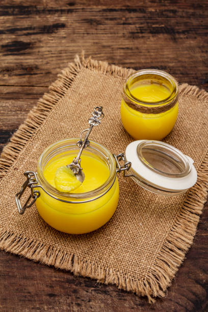 Pure or desi ghee (ghi), clarified melted butter. Healthy fats bulletproof diet concept or paleo style plan. Glass jars, silver spoon on vintage sackcloth. Wooden boards background Pure or desi ghee (ghi), clarified melted butter. Healthy fats bulletproof diet concept or paleo style plan. Glass jars, silver spoon on vintage sackcloth. Wooden boards background, copy space ghee stock pictures, royalty-free photos & images
