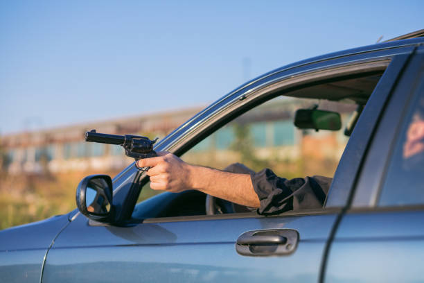 criminal discharging a gun through a window of a moving car - gun handgun violence kidnapping imagens e fotografias de stock