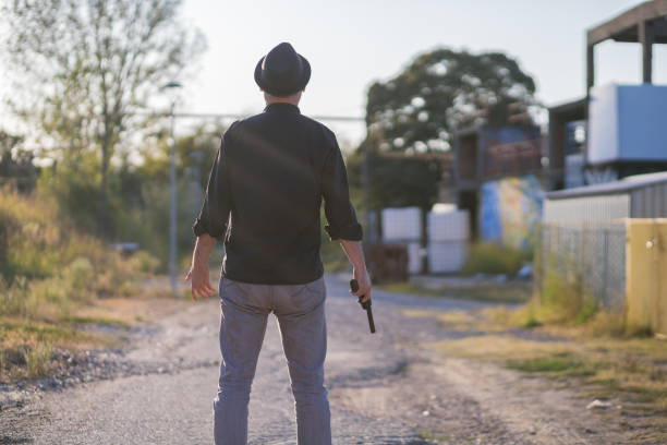 criminel avec chemise foncée, chapeau, et réplique d'arme à feu - gun handgun violence kidnapping photos et images de collection