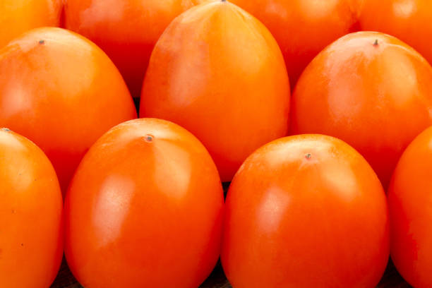 Organic persimmon fruit in pile at local farmers market. Fresh ripe persimmons placed on table in form of background.