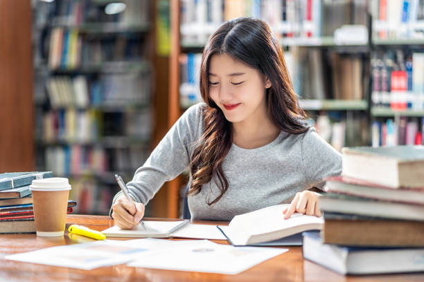 Asian young Student in casual suit reading and doing homework in library of university stock photo