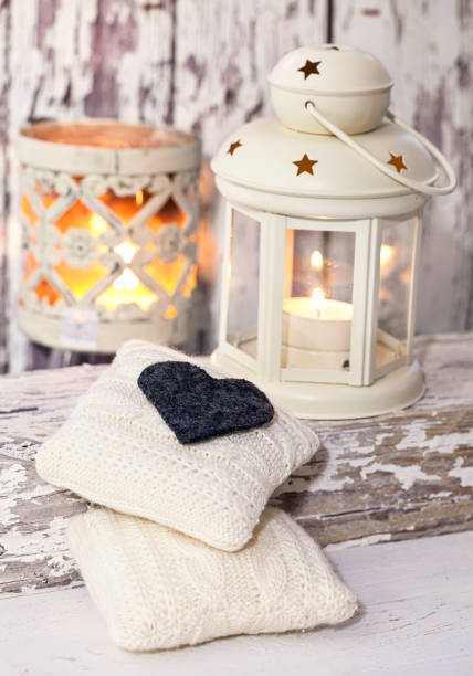 A rustic winter or Christmas deocoration in a white interior, with lanterns, felt heart and knitted deocor objects