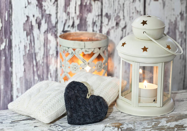 A rustic winter or Christmas deocoration in a white interior, with lanterns, felt heart and knitted deocor objects