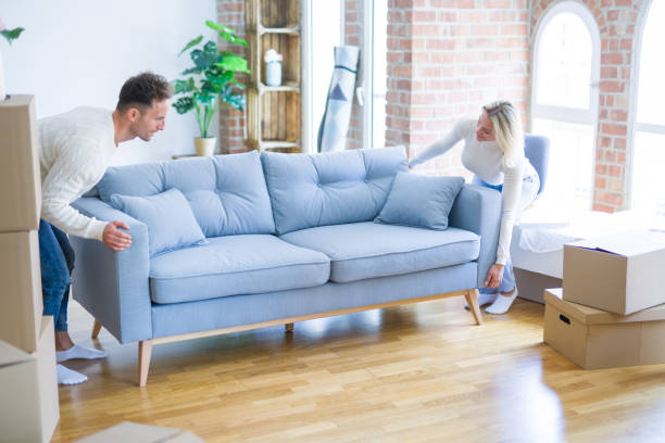 istock Young beautiful couple moving sofa at new home around cardboard boxes 1187188752