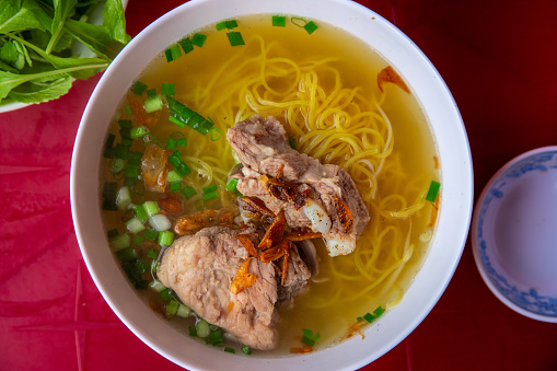 Soup Pho with noodles and meat, top view photo of vietnamese cuisine served on red table. Pho Bo traditional dish of Vietnam. Tasty rich broth with noodles and meat. Lunch food recipe. Travel in Asia
