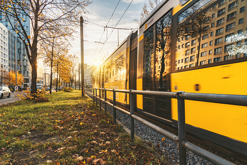 yellow street car in the backlit of autumm sun in front of TV-Tower