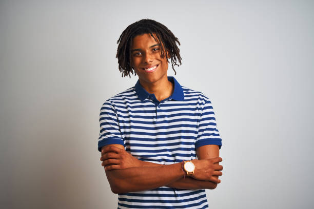 istock Afro man with dreadlocks wearing striped blue polo standing over isolated white background happy face smiling with crossed arms looking at the camera. Positive person. 1187191155