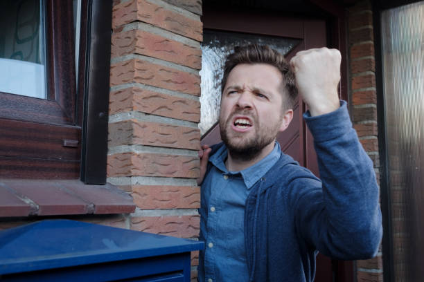 Angry upset young male neighbor with fist in air, open mouth yelling. stock photo
