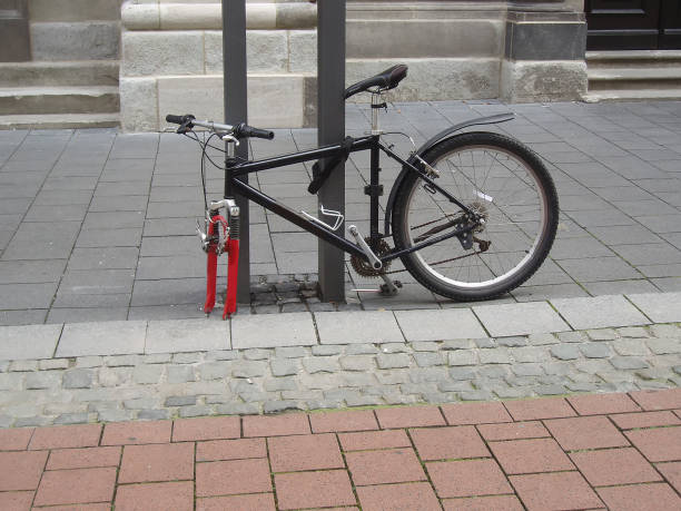 A bicycle fastened to a post stands on the street. One wheel stolen from a bicycle. stock photo