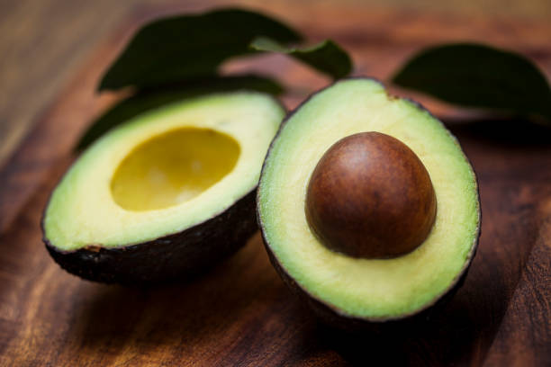 istock Avocado halves on wooden board with leaves 1187201864