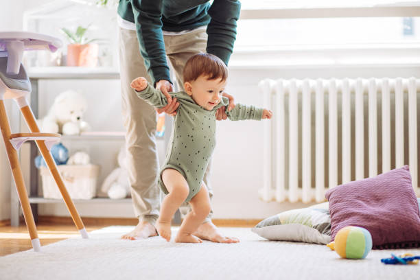 Baby learn to walk Young father helping baby to practice walking, they are home and enjoy in time they spending together first steps stock pictures, royalty-free photos & images