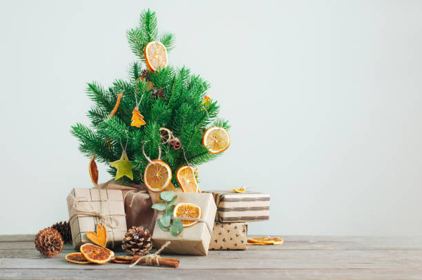 dried citrus slices on the christmas tree with craft paper wrapping gift boxes - gift orange green package imagens e fotografias de stock