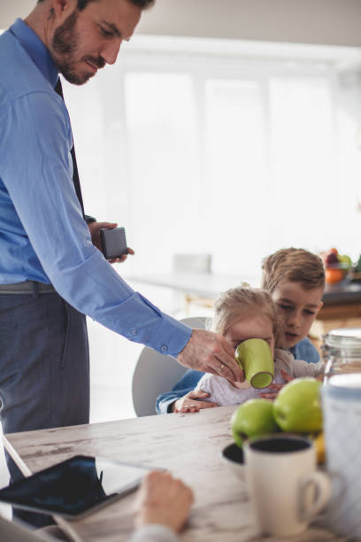 istock Father helping his little daughter drink her tea at breakfast 1187203942
