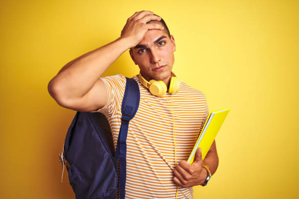 istock Young student man wearing headphones and backpack over yellow isolated background stressed with hand on head, shocked with shame and surprise face, angry and frustrated. Fear and upset for mistake. 1187204365