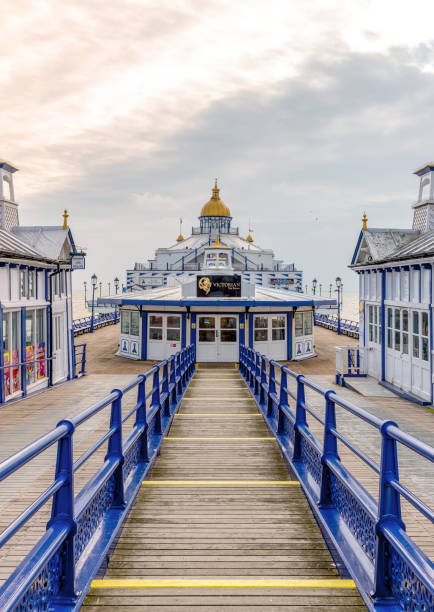 Seaside pier. Eastbourne pier with a walkway to a cafe.  Shops with pagoda style domes are on wither side and a cloudy sky is above. eastbourne pier photos stock pictures, royalty-free photos & images