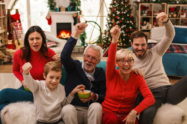 istock Family cheering with their arms raised while watching TV together 1187204617