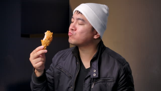 4K Footage Teenagers wear winter clothes, He is holding fried chicken legs and He is eating delicious fried chicken.