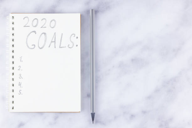 istock 2020 new year goals, plan, action text on notepad on white marble background. 2020 goals on blank note paper with copy space for text 1187205668