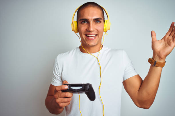 istock Young handsome man playing videogames using headphones over white isolated background very happy and excited, winner expression celebrating victory screaming with big smile and raised hands 1187208417