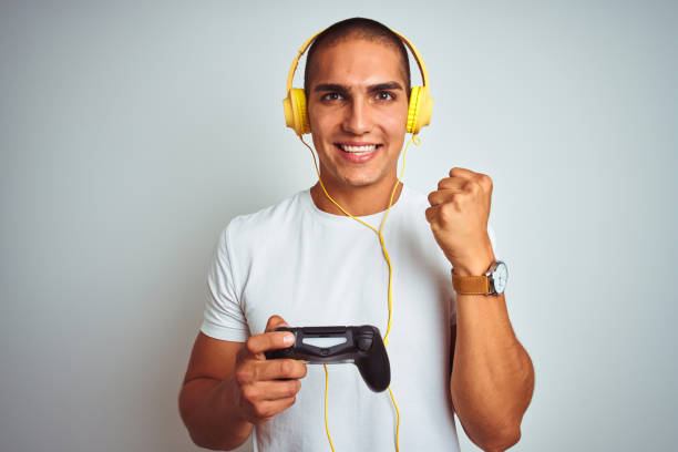 istock Young handsome man playing videogames using headphones over white isolated background screaming proud and celebrating victory and success very excited, cheering emotion 1187208457