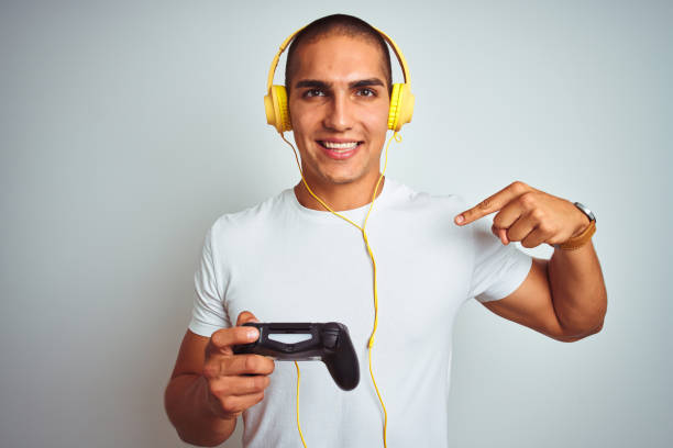 istock Young handsome man playing videogames using headphones over white isolated background with surprise face pointing finger to himself 1187208497