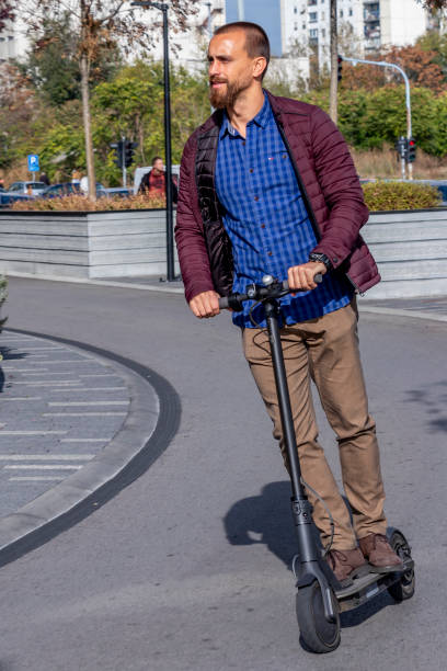 istock Modern young man riding electric scooter through city 1187208546