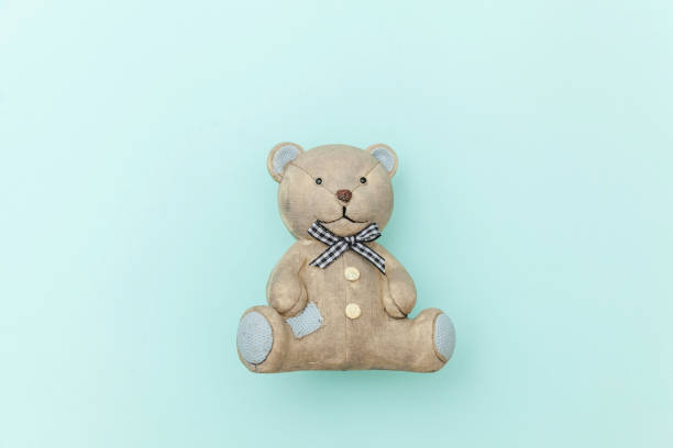 Children's toys teddy bears sitting on a white sofa in a knitted white and blue scarf and hat. Selective focus.