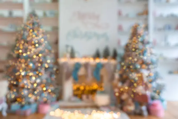 Blurred living room Christmas New year interior with light bokeh effect and Christmas tree with presents under it