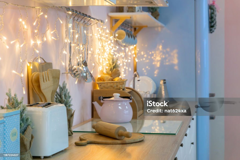 Pink white and blue kitchen interior and kitchenware on holidays, christmas light and decoration garland and wreath Christmas Stock Photo
