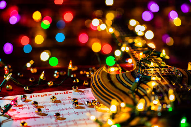 Jingle Bells, in the public domain since 1952, is a favorite of holiday celebrations   Close up shot of Guitar Music for the holiday season.  Jingle Bells sheet music and Christmas lights accompany a beautiful laminated wood electric guitar. Guitar Music for the holiday season.  Jingle Bells sheet music, Christmas lights and small bells accompany a beautiful laminated wood electric guitar.  Focus is on the Sheet Music title Jingle Bells and the bells on the table and is very shallow.  foreground and background are a very soft Bokeh of a string of holiday lights.  featuring plenty of space for copy writing on the background with the bokeh of the lights. public domain images stock pictures, royalty-free photos & images