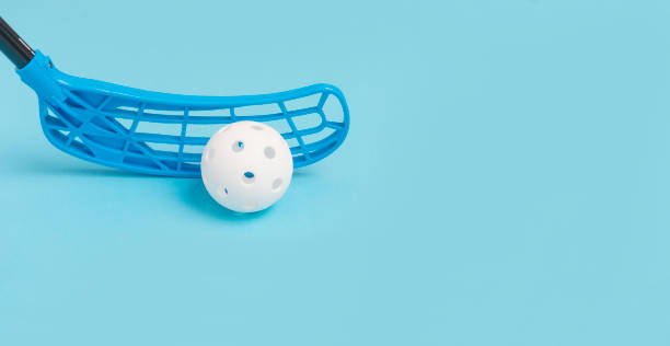 floorball stick and white ball isolated on blue background - teamsport imagens e fotografias de stock