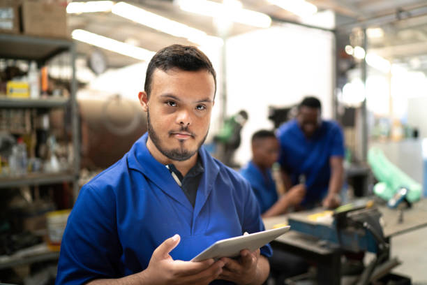 portrait of special needs employee holding a digital tablet in industry - auto repair shop adult auto mechanic blue imagens e fotografias de stock