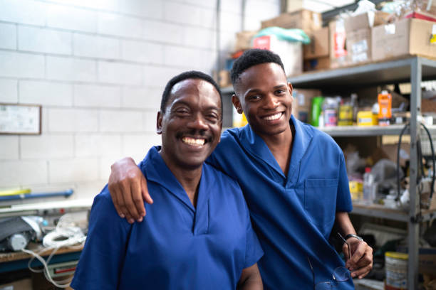 portrait of happy colleagues or father and son in industry - auto repair shop adult auto mechanic blue imagens e fotografias de stock