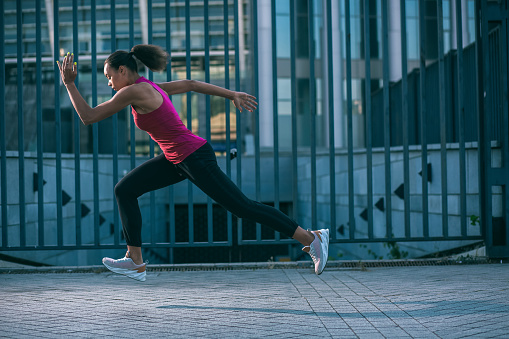 Professional sportswoman in the street running quickly alone. Template banner