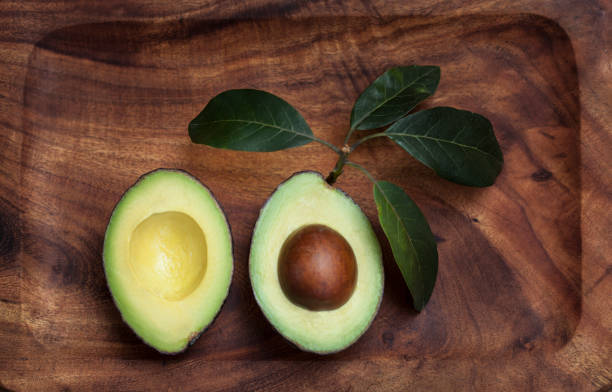istock Avocado halves on wooden board with leaves, flat lay, top view 1187238603