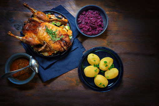 Pato asado con patatas, repollo rojo y salsa, una comida festiva en una mesa de madera rústica oscura, espacio de copia, vista de alto ángulo desde arriba photo