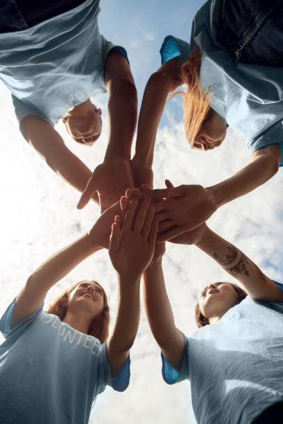 istock Volunteering. Young people volunteers outdoors standing hands together close-up bottom view smiling excited 1187245664