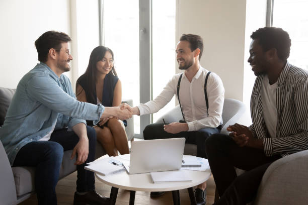 istock Smiling confident business partners shaking hand at group negotiations 1187245859