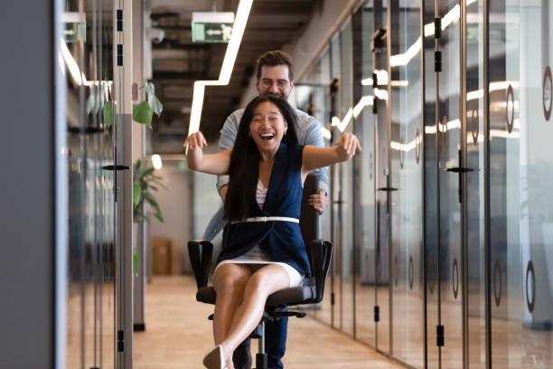 istock Diverse colleagues having fun, riding on office chair in hallway 1187245884