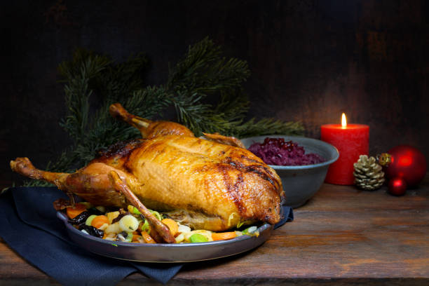istock Roasted duck as Christmas menu with red cabbage and vegetables, a festive meal on a rustic wooden table with burning candle and decoration, dark brown background with copy space, selected focus, narrow depth of field 1187247979