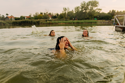 Photo of smiling girlfriends swimming in a lake