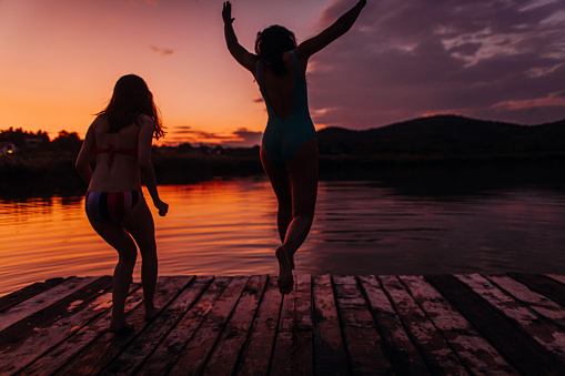 Photo of girlfriends jumping into the lake