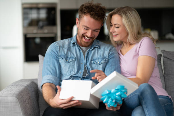 istock Happy man opening a gift from his girlfriend at home 1187250858
