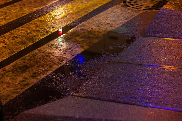 puddle at the crosswalk urban night lights. wet surface reflection asphalt stone